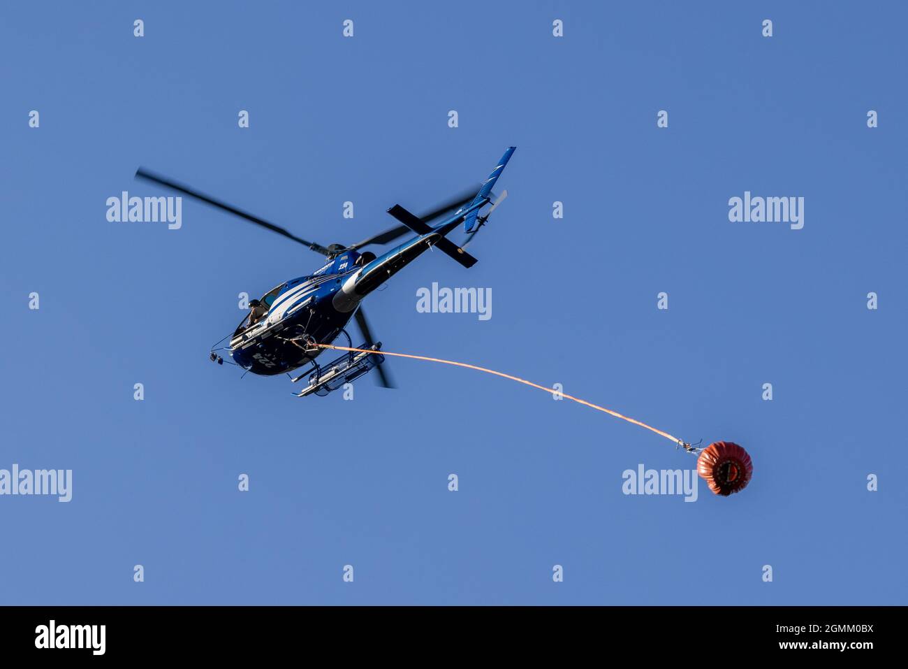Helicopter carrying water bucket to control bush fire Stock Photo Alamy