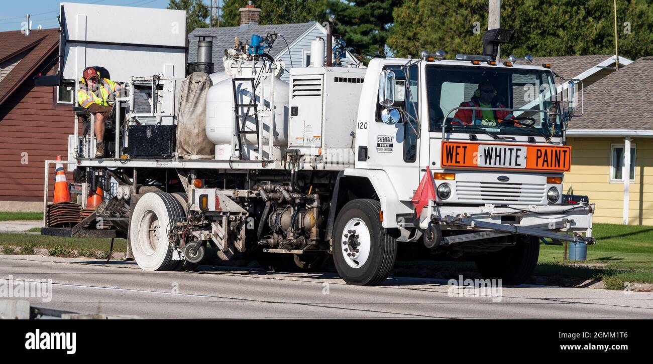 Highway maintenance workers and vehicle painting white center line on road pavement. Stock Photo