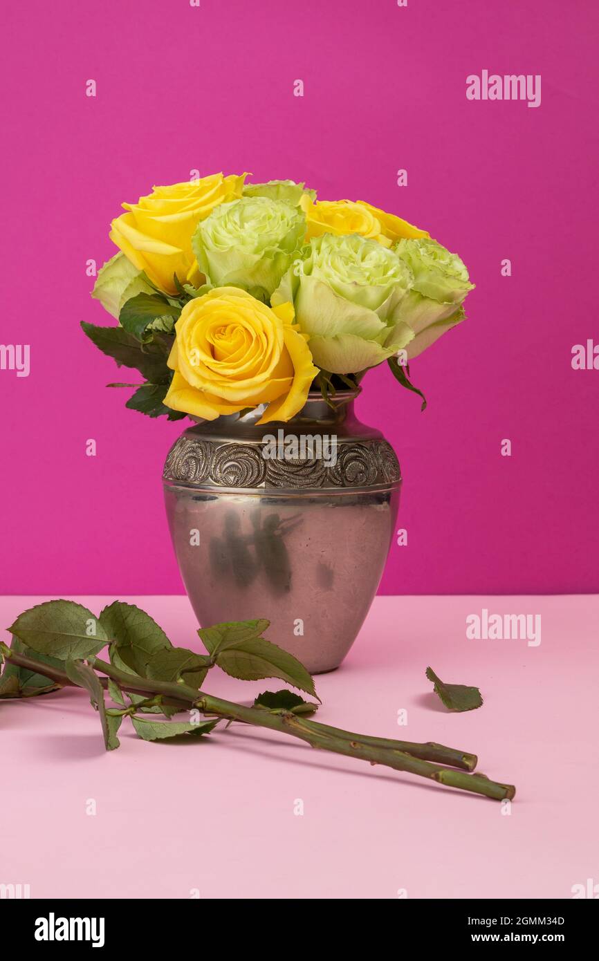 flower arrangement with yellow and white roses inside a metal vase