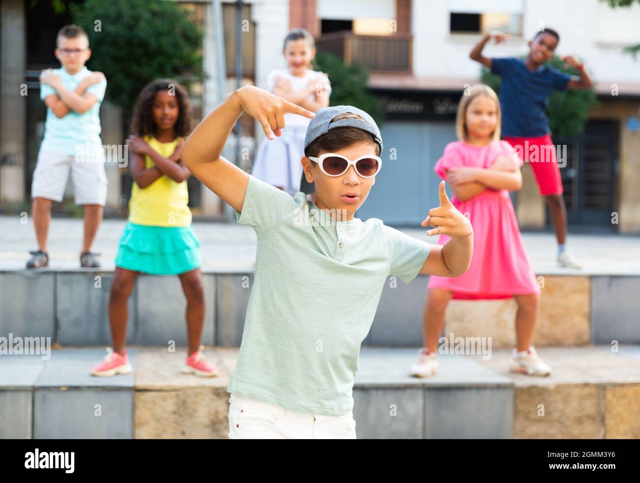 Preteen boy in sunglasses dancing krump with tweens on city street Stock Photo