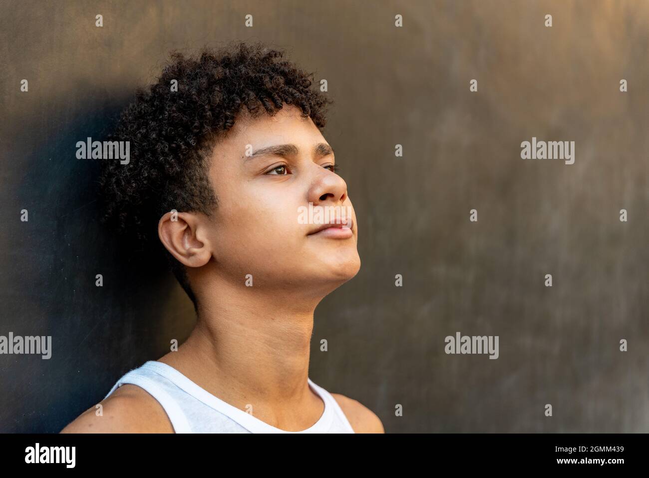 Afro latin male teenager against a wall, looking up. Stock Photo