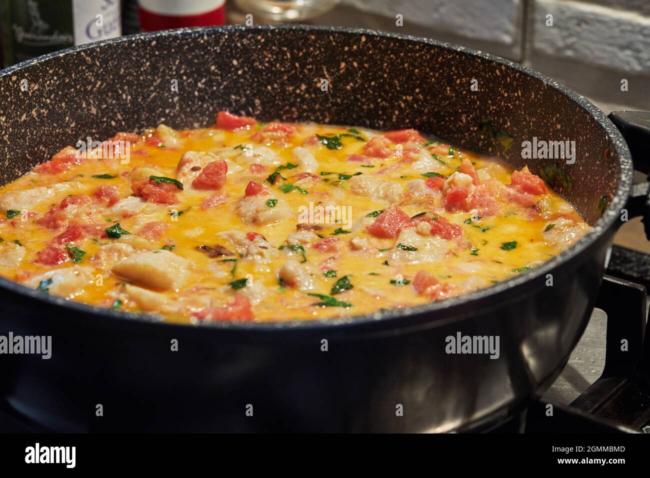 Bass fish with fennel tomatoes and basil are fried in pan on the gas stove. Stock Photo