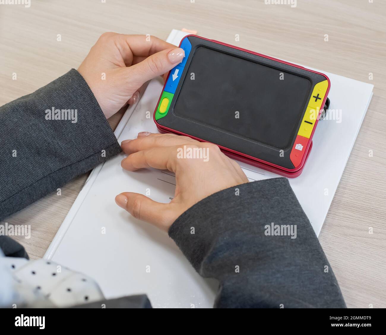 The woman is holding a reading device for the visually impaired