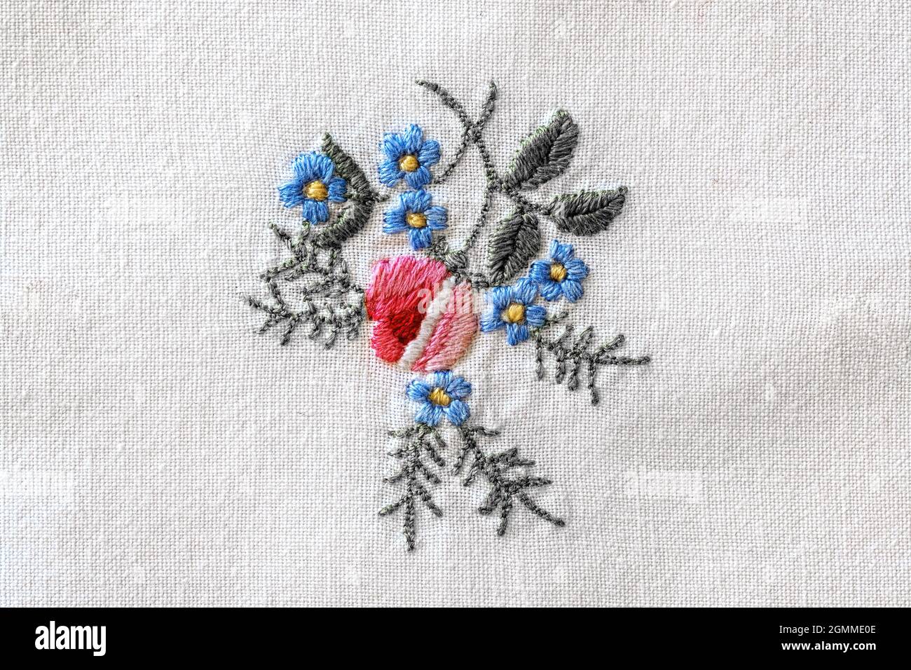 close up of a colorful flower embroidery on old white tablecloth Stock Photo