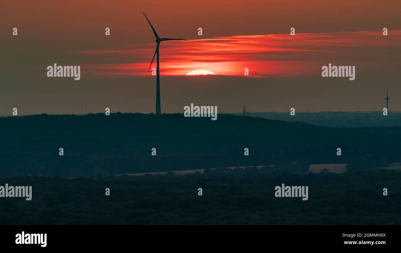 The setting sun and some wind turbines in the Ruhr Area, seen from the Halde Haniel, Bottrop, North Rhine-Westfalia, Germany Stock Photo