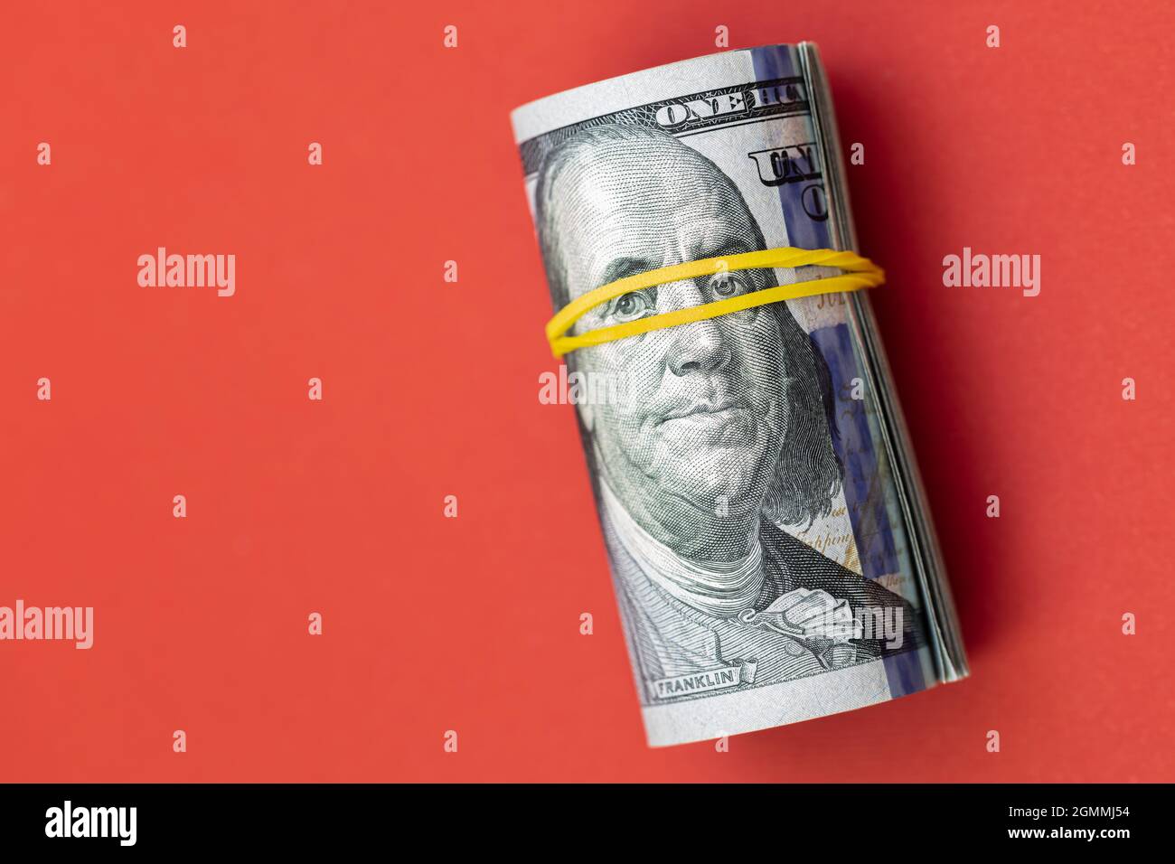 roll of 100 dollar banknotes on red background Stock Photo - Alamy