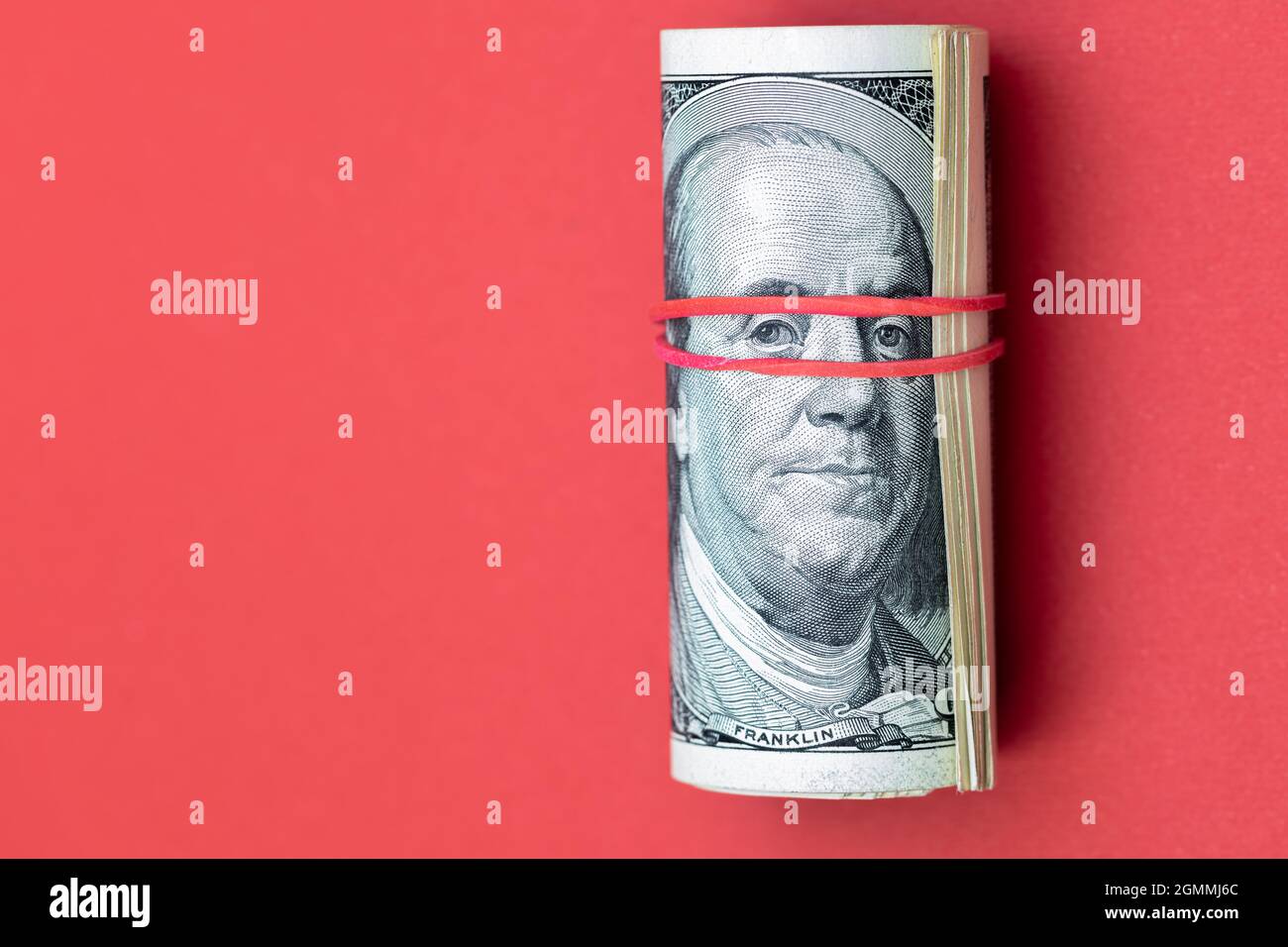 roll of 100 dollar banknotes on red background Stock Photo - Alamy