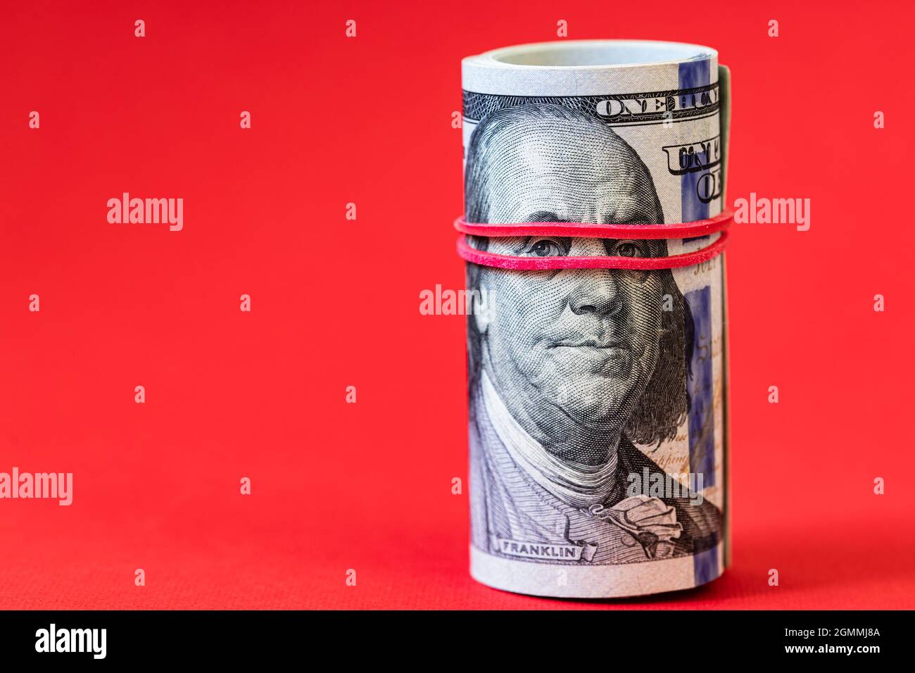 roll of 100 dollar banknotes on red background Stock Photo - Alamy