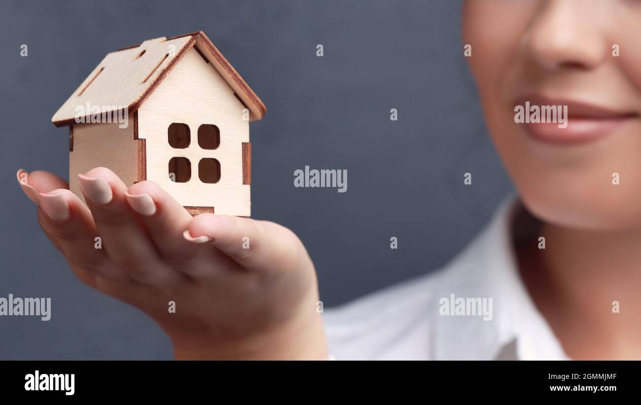 This is a small wooden house in the palm of a beautiful girl close-up ...