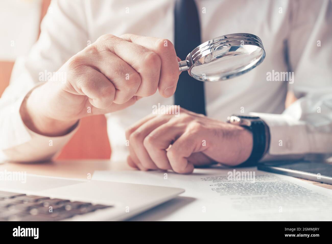 Cautious businessman reading contract agreement with magnifying glass, close up with selective focus Stock Photo