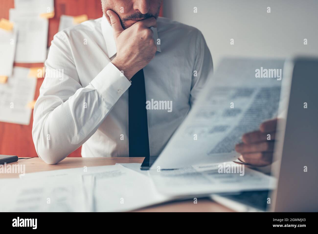Businessman reading business report document at office desk, close up with selective focus Stock Photo