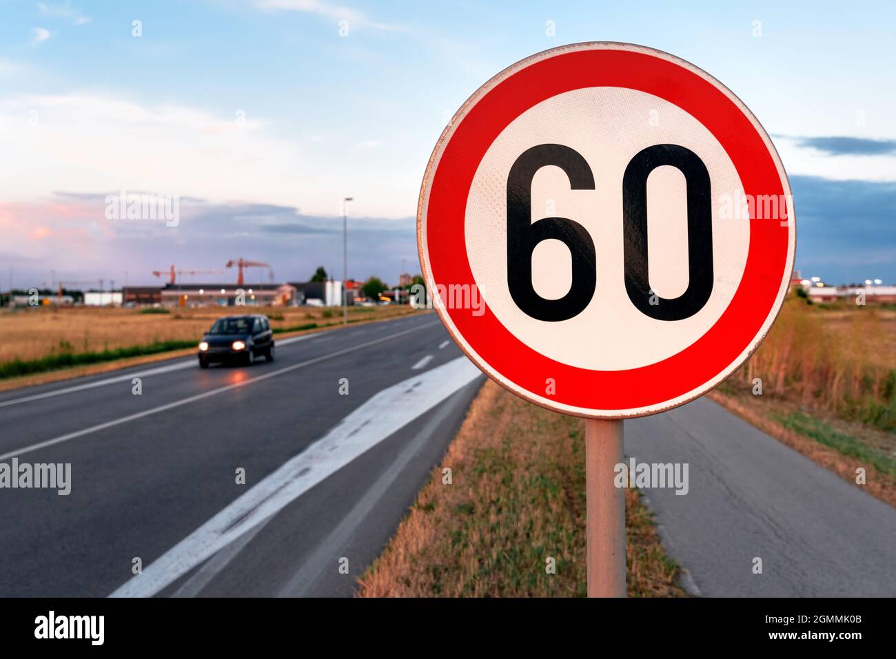 Speed limit at 60 kmph traffic sign by the road, blurred car in motion in background Stock Photo
