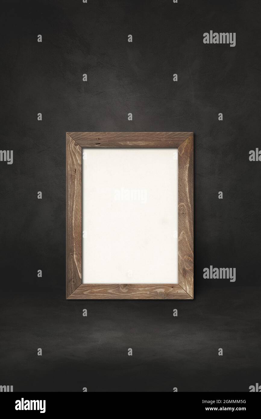 Wooden picture frame leaning on a black wall. Presentation mockup ...