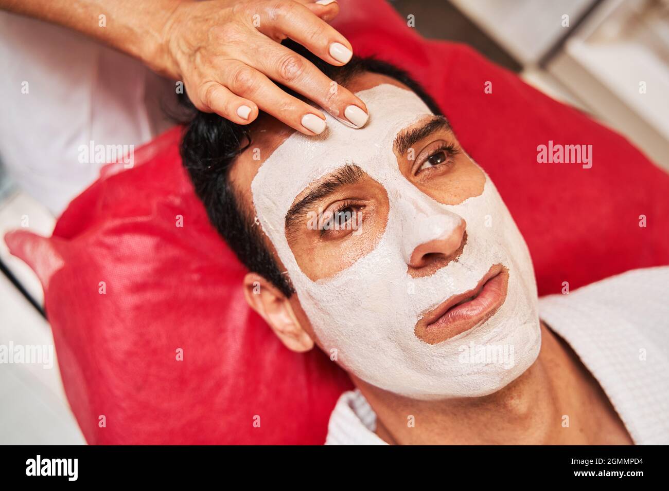 Beauty specialist applying facial pack on adult forehead Stock Photo