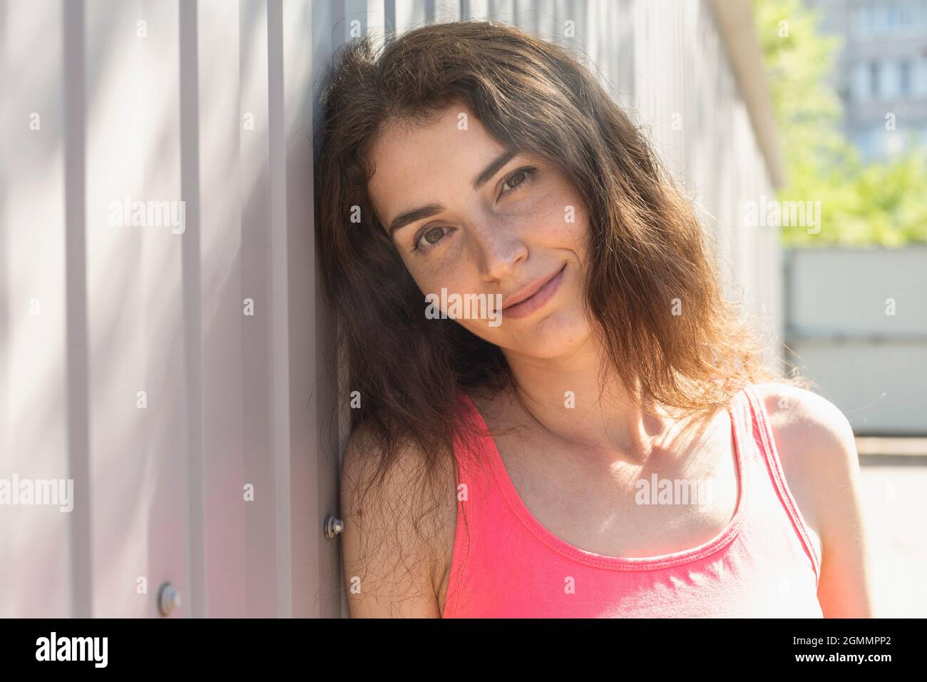 Portrait beautiful smiling young woman leaning against wall Stock Photo