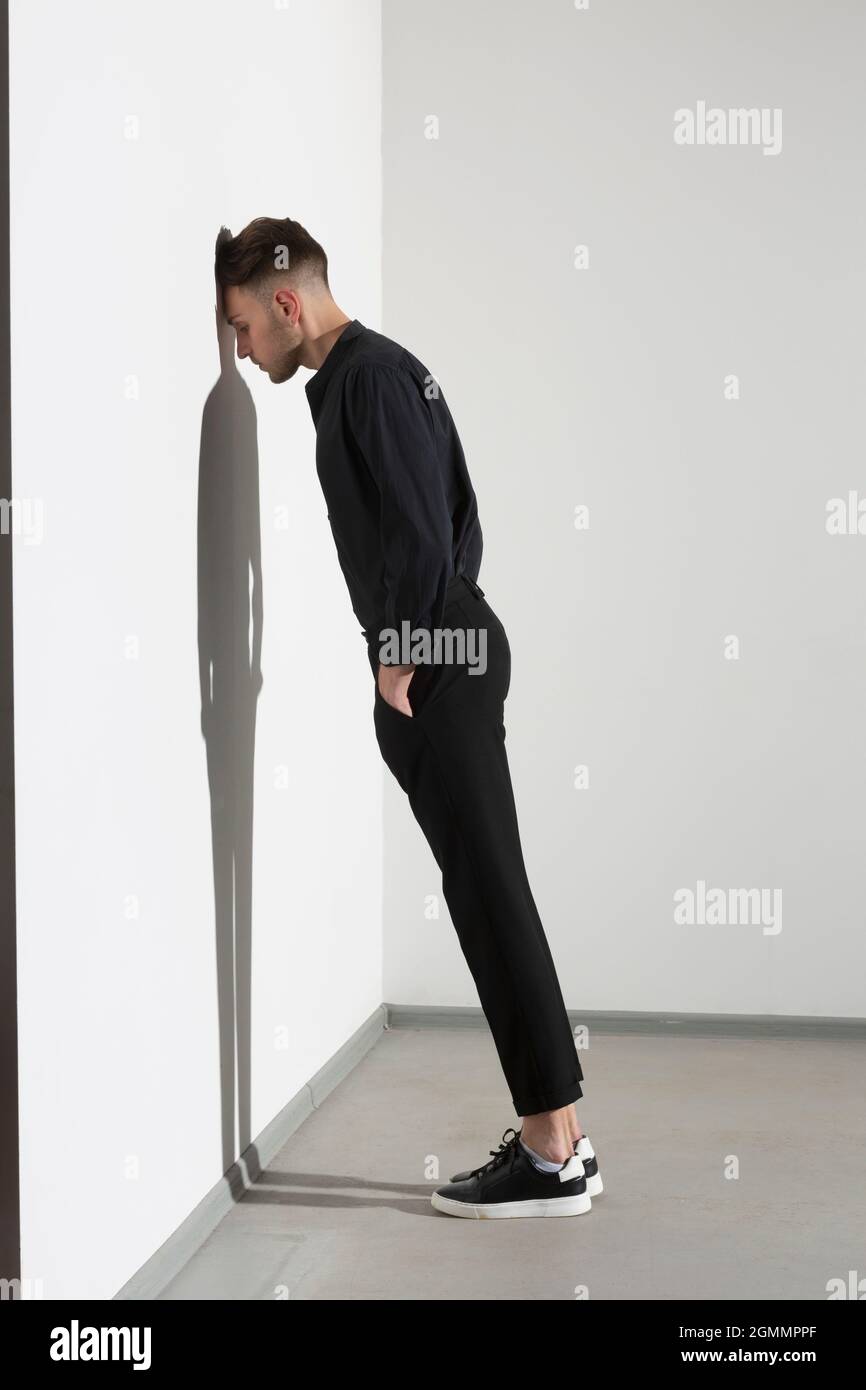 Man leaning against white wall Stock Photo