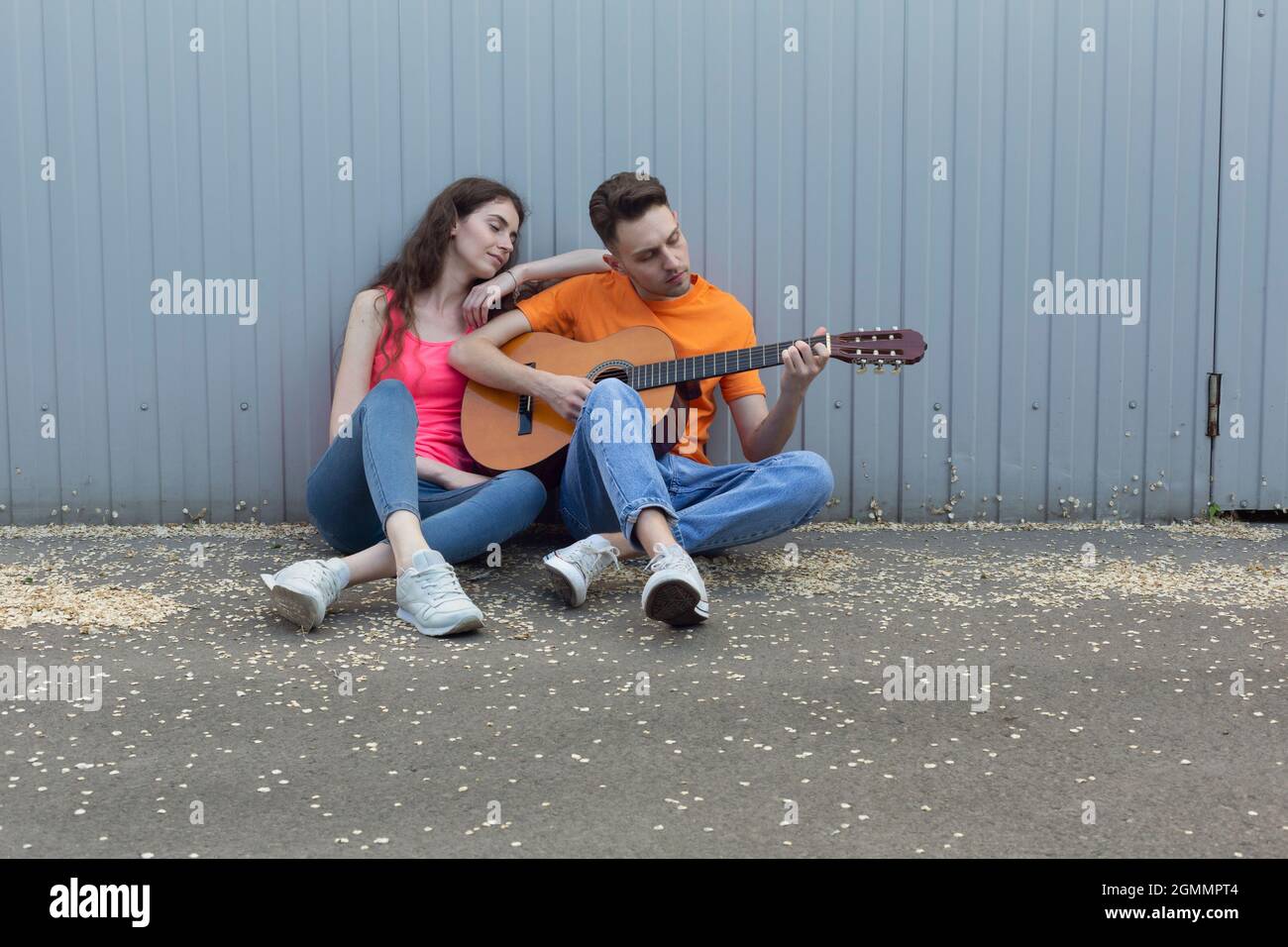 Young couple playing guitar at wall Stock Photo