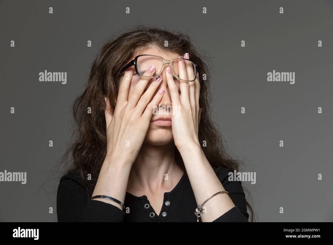 Tired young woman rubbing eyes Stock Photo