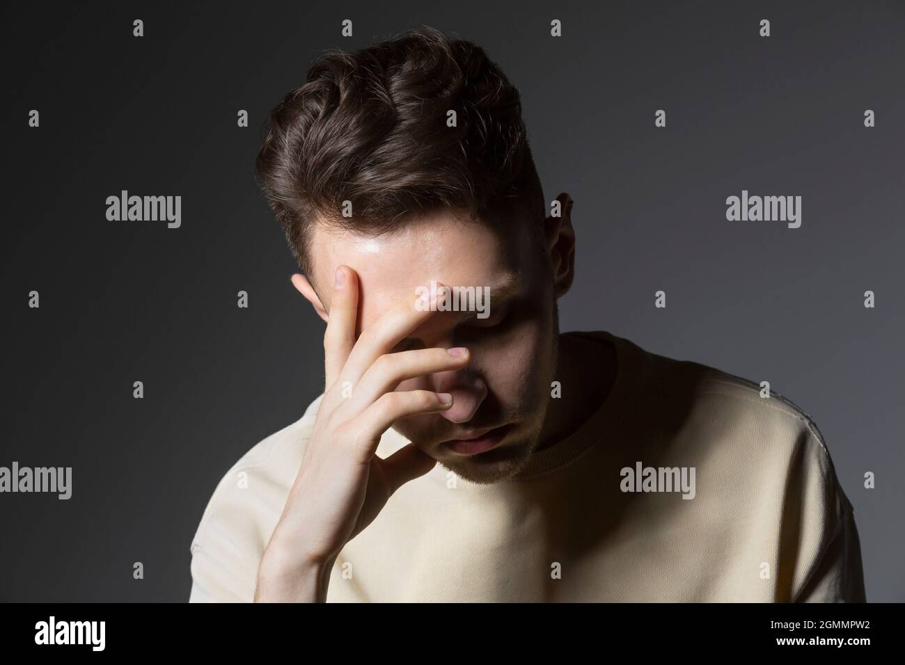Tired young man with head in hands Stock Photo