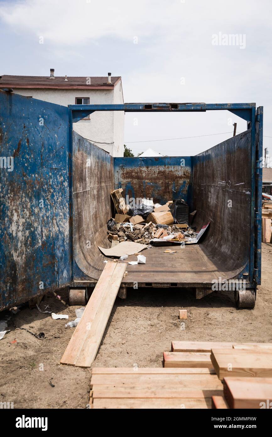 Wood plank leaning against dumpster with garbage Stock Photo Alamy