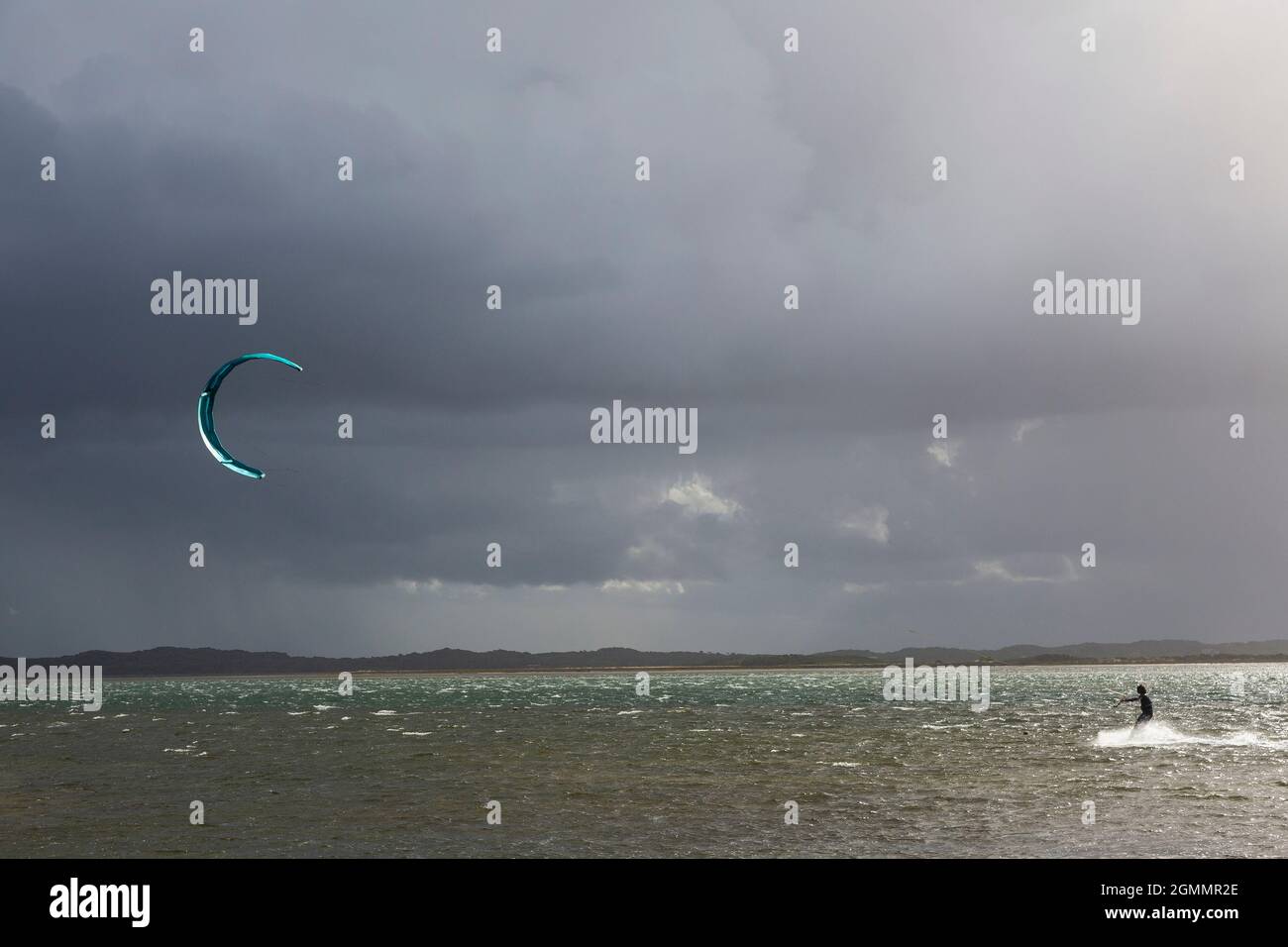 Kite boarder on ocean below stormy cloudy sky Stock Photo