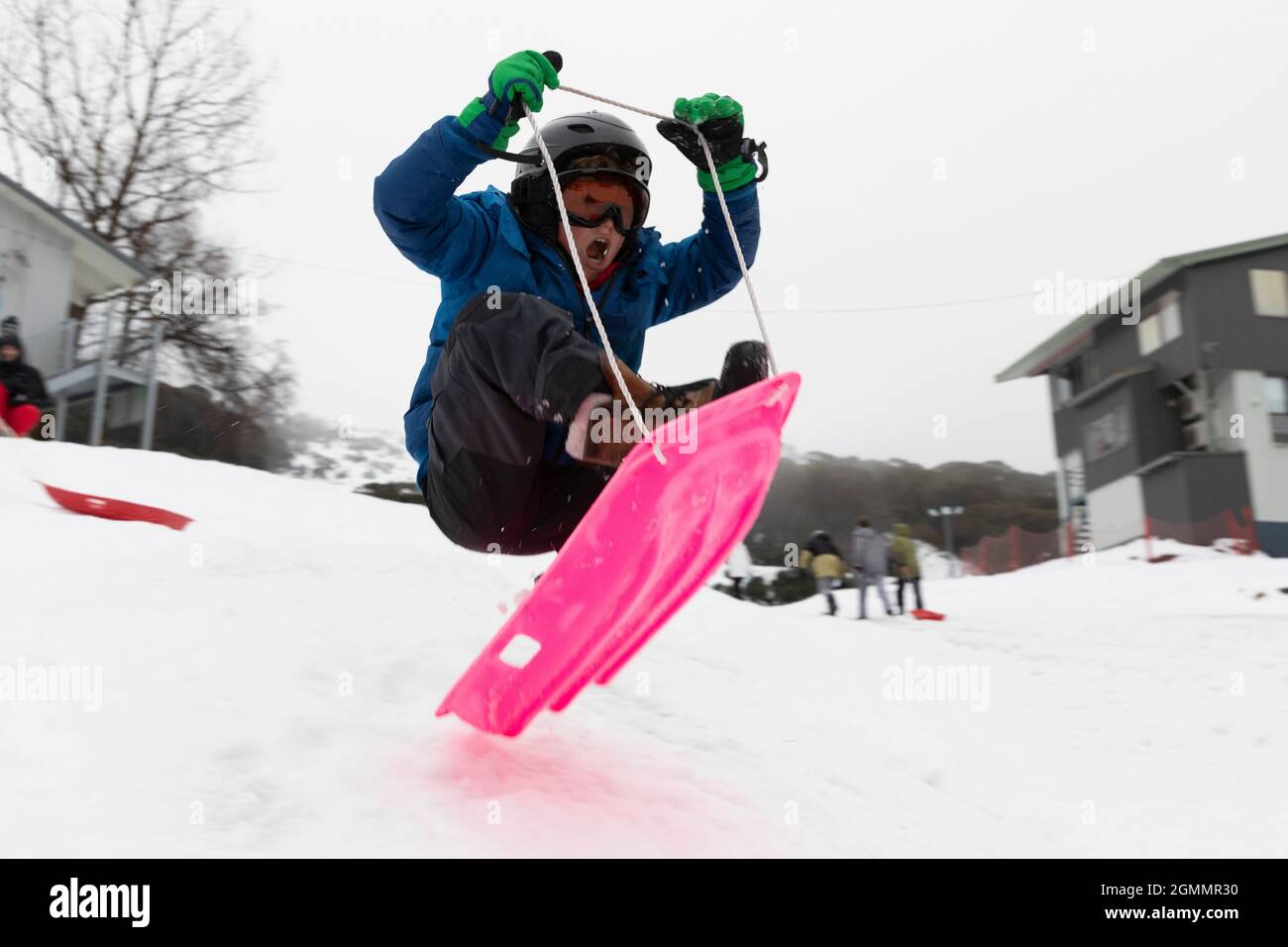 Boy sledding on snowy slope Stock Photo