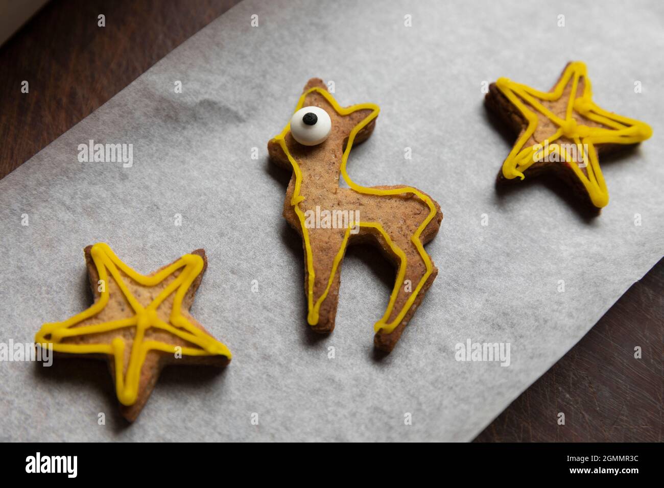 Decorated gingerbread reindeer and stars on parchment paper Stock Photo