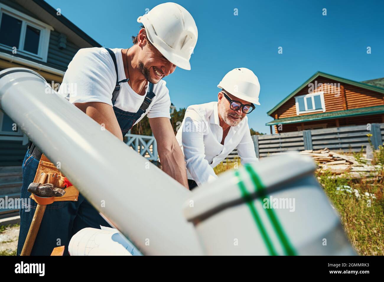 Construction workers in helmets leaning over table Stock Photo