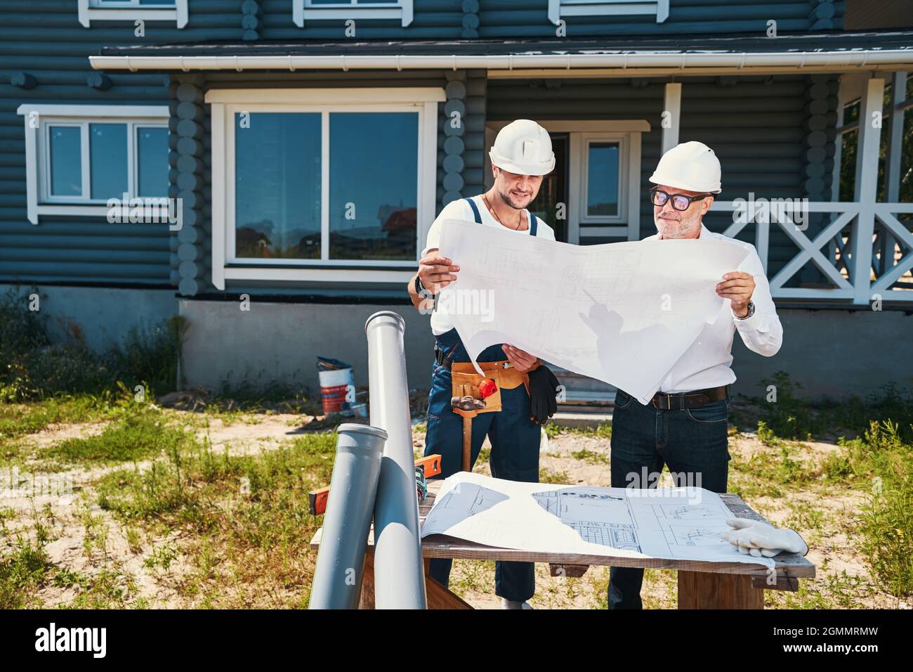 Pair of housebuilders inspecting building layouts outdoor Stock Photo