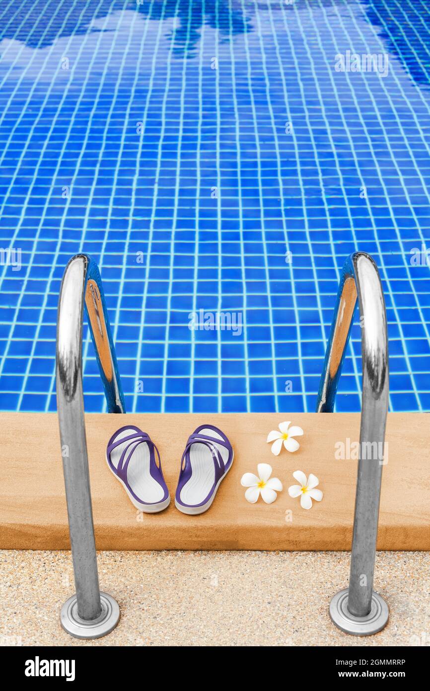 Swimming pool blue water, white plumeria frangipani flowers, women flip flops, poolside, tropical sea beach nature, summer holidays, vacation, spa Stock Photo