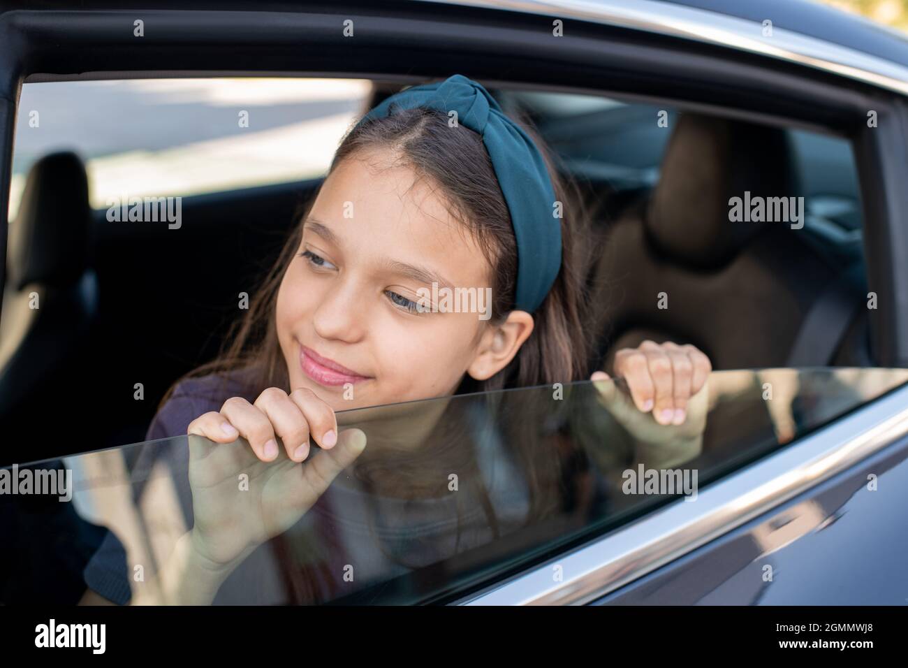 https://c8.alamy.com/comp/2GMMWJ8/adorable-schoolgirl-looking-out-of-window-of-electric-car-while-sitting-inside-2GMMWJ8.jpg
