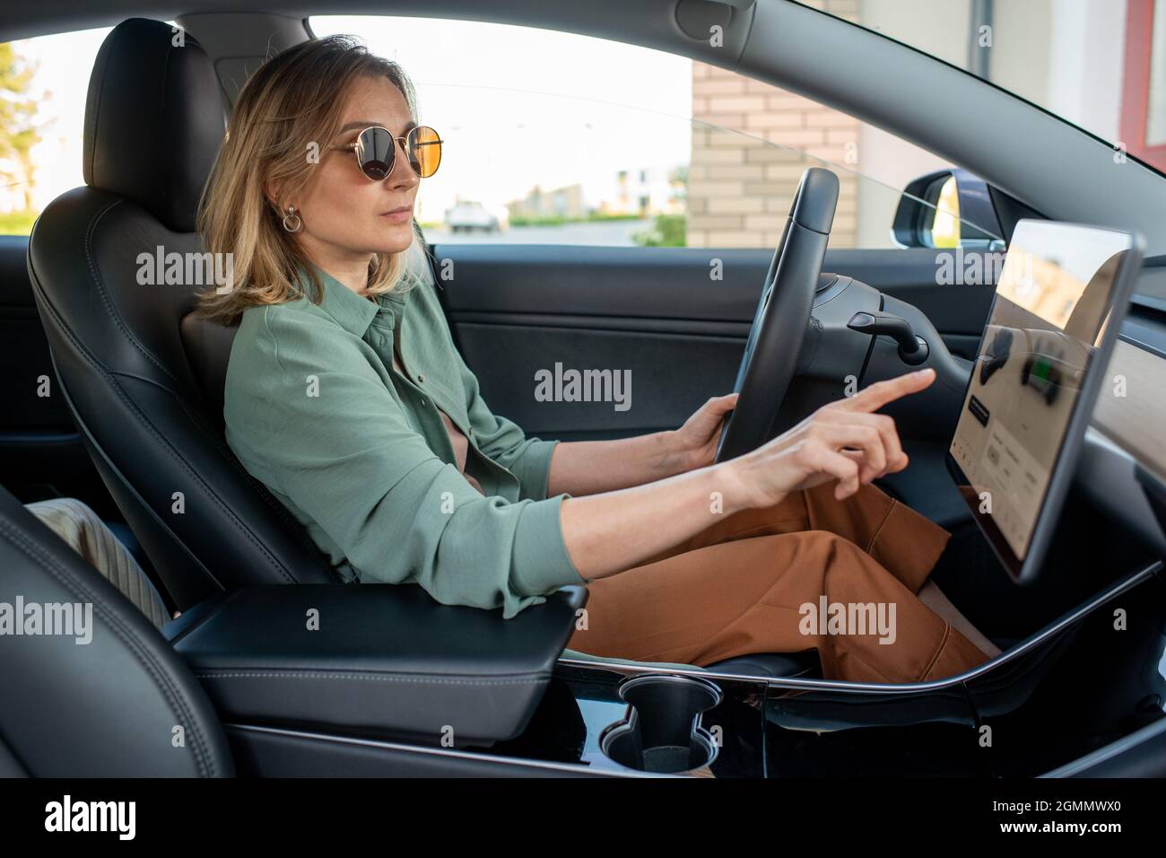 Young female driver sitting in car and pointing at display while choosing destination place Stock Photo