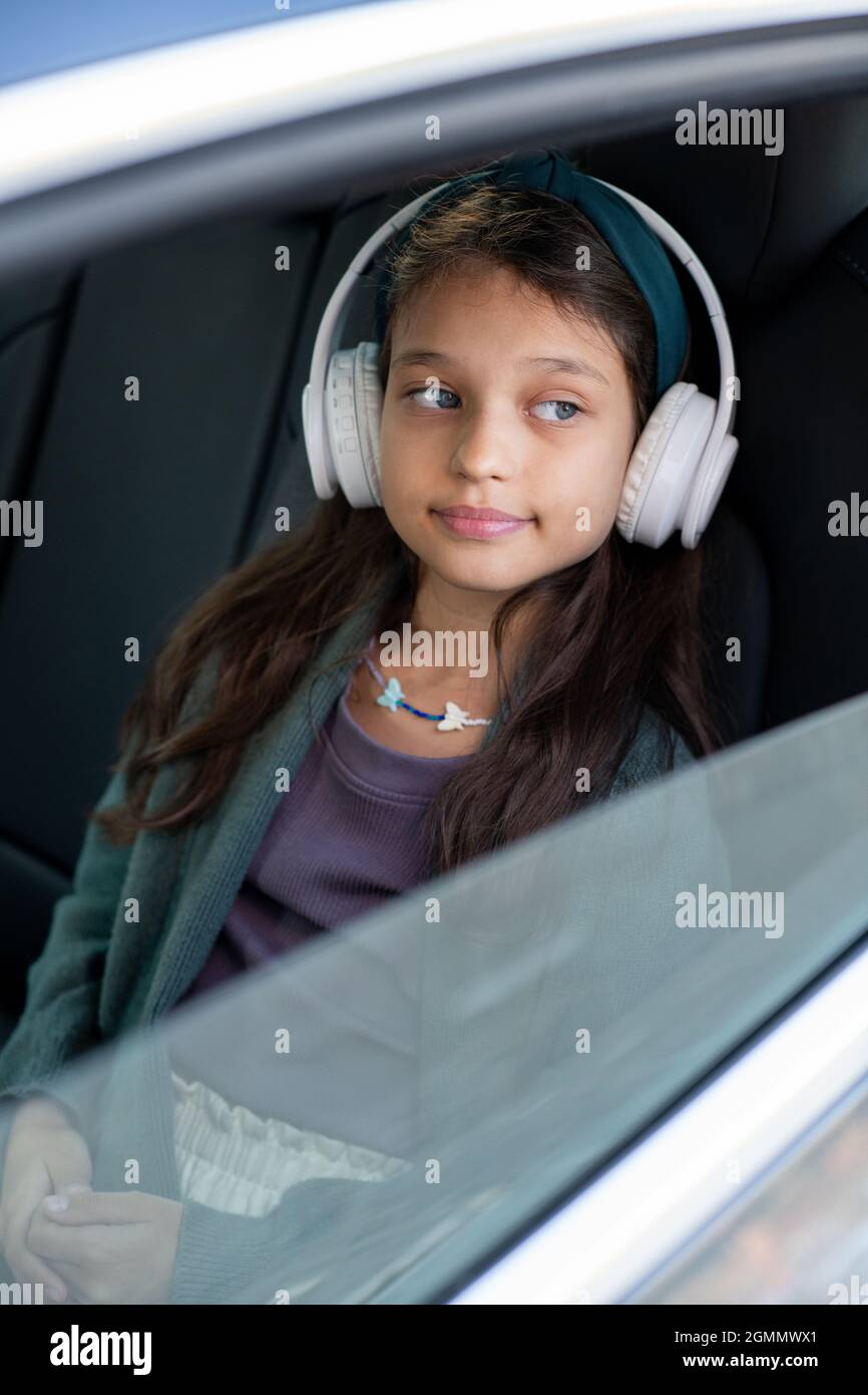 Cute little girl listening to music in headphones while sitting on