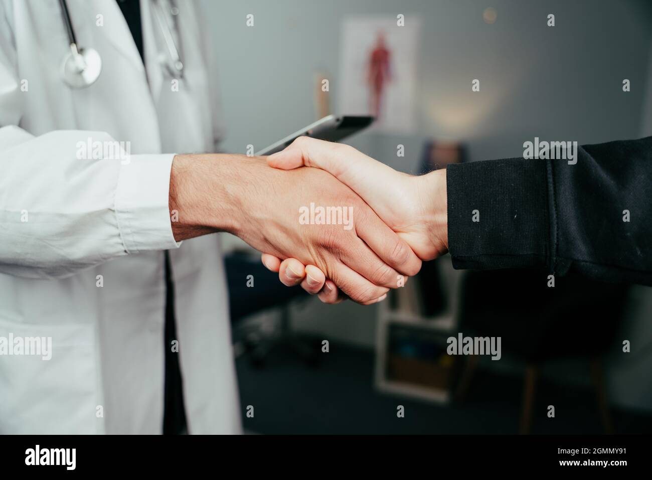 Close up male nurse holding digital tablet shaking hands with caucasian patient Stock Photo