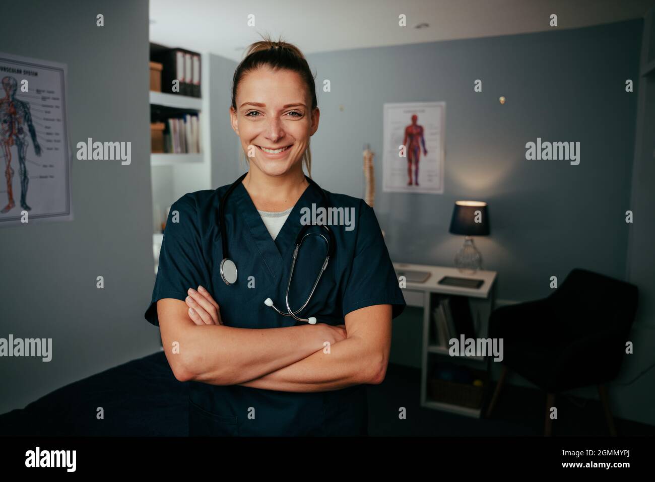 Caucasian female nurse standing with arms crossed in medical clinic Stock Photo