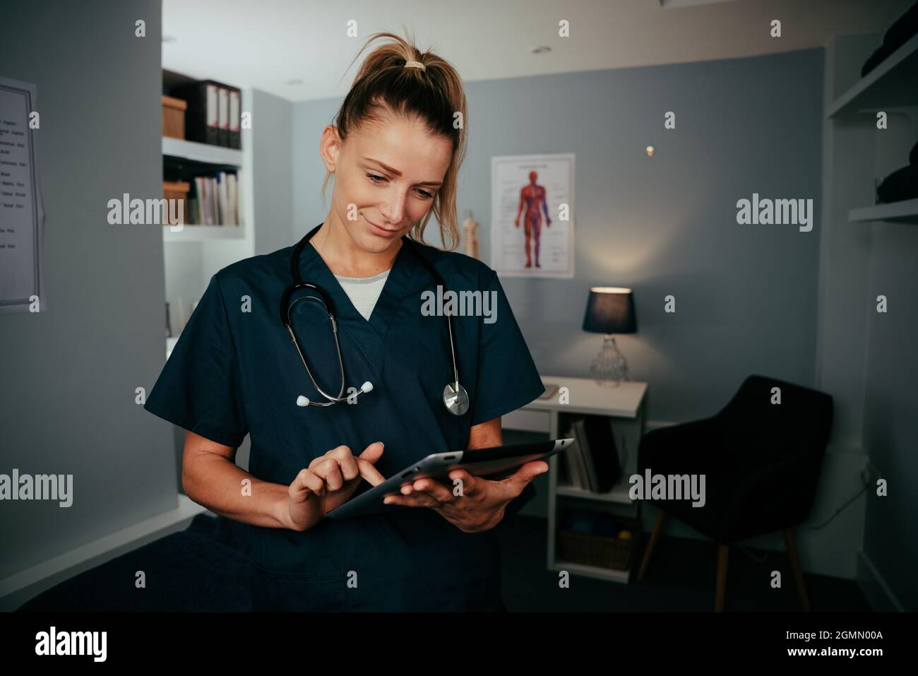 Caucasian female doctor working in clinic typing on digital tablet Stock Photo