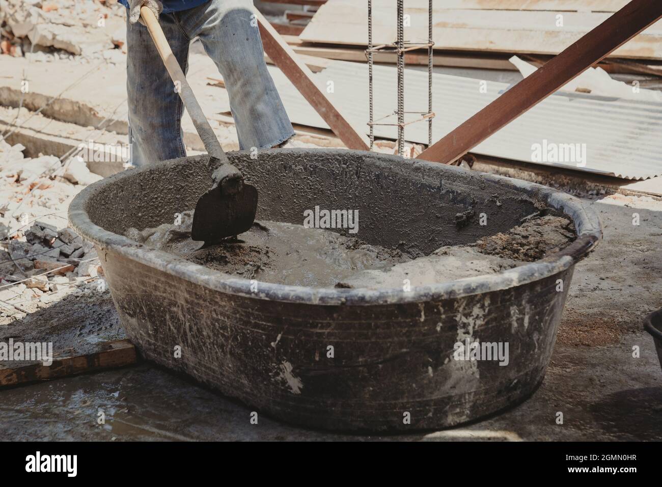 Worker man house builder mix mortar from a trough in bucket Stock Photo