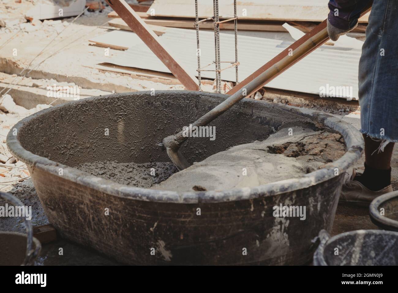 Worker man house builder mix mortar from a trough in bucket Stock Photo