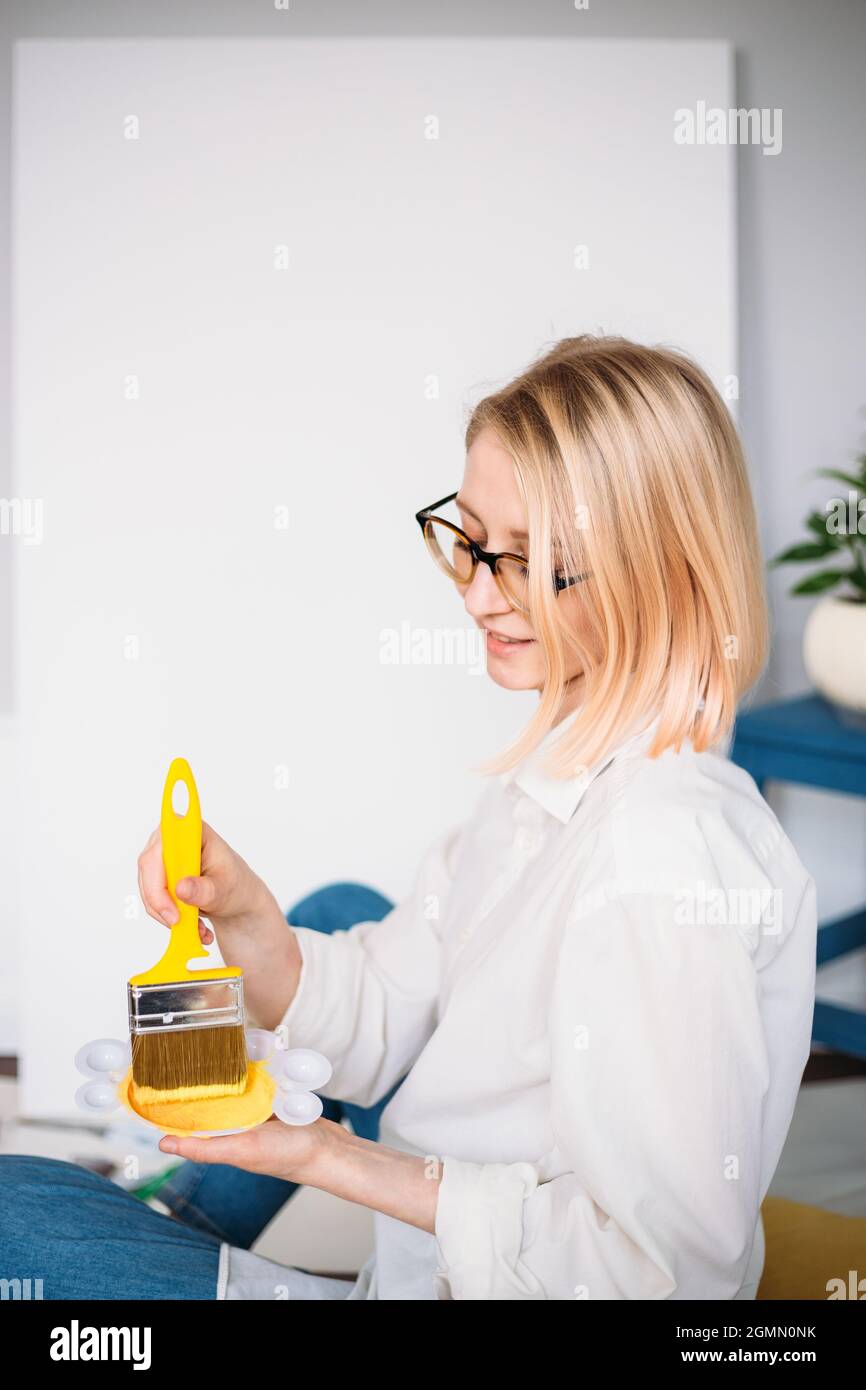 Young woman artist is painting at home in a creative studio setting.  Stock Photo