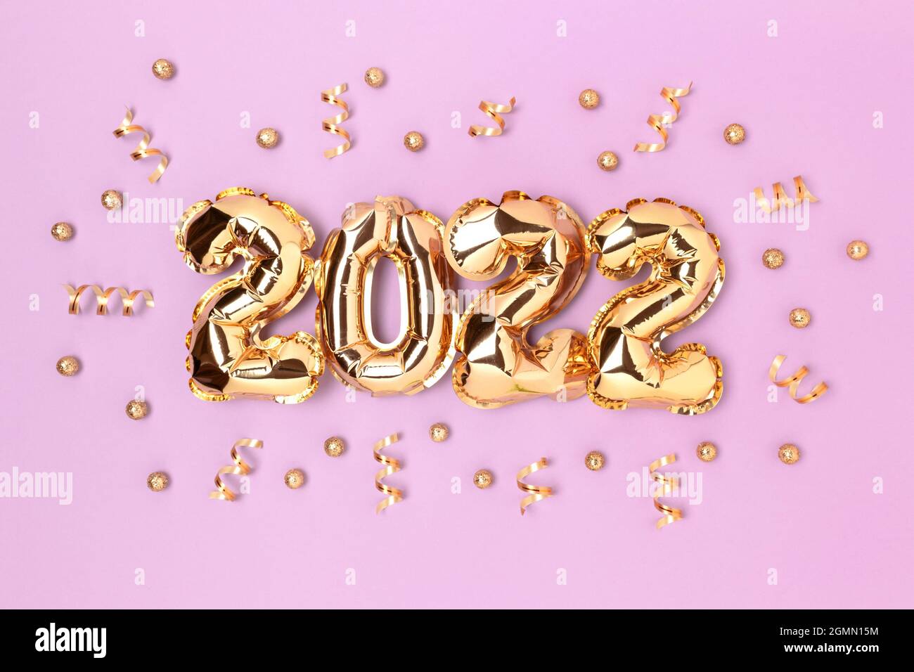 2022 gold inflatable balloons and confetti on a purple background. Holidays concept. Stock Photo