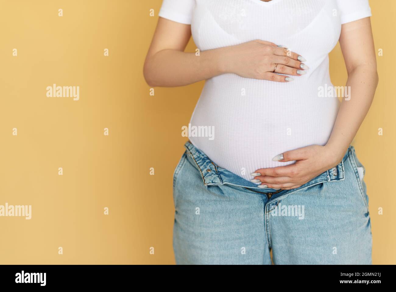 Pregnant woman in blue jeans, hat and unbuttoned black shirt posing on gray  background Stock Photo - Alamy