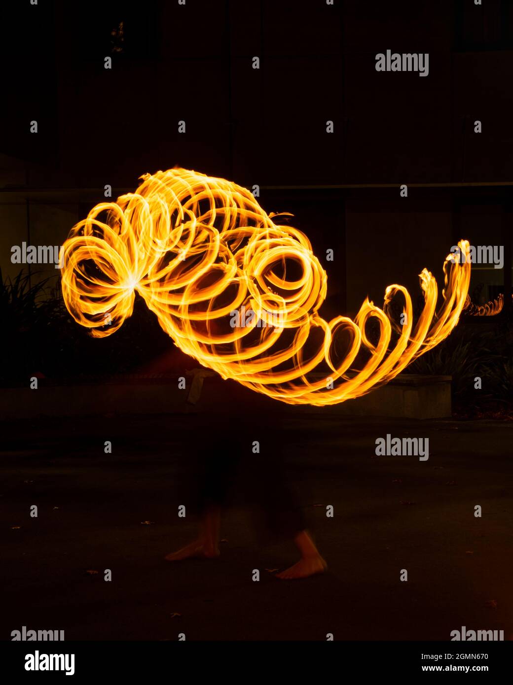 Street artist juggling with burning poi at fire performance. Long