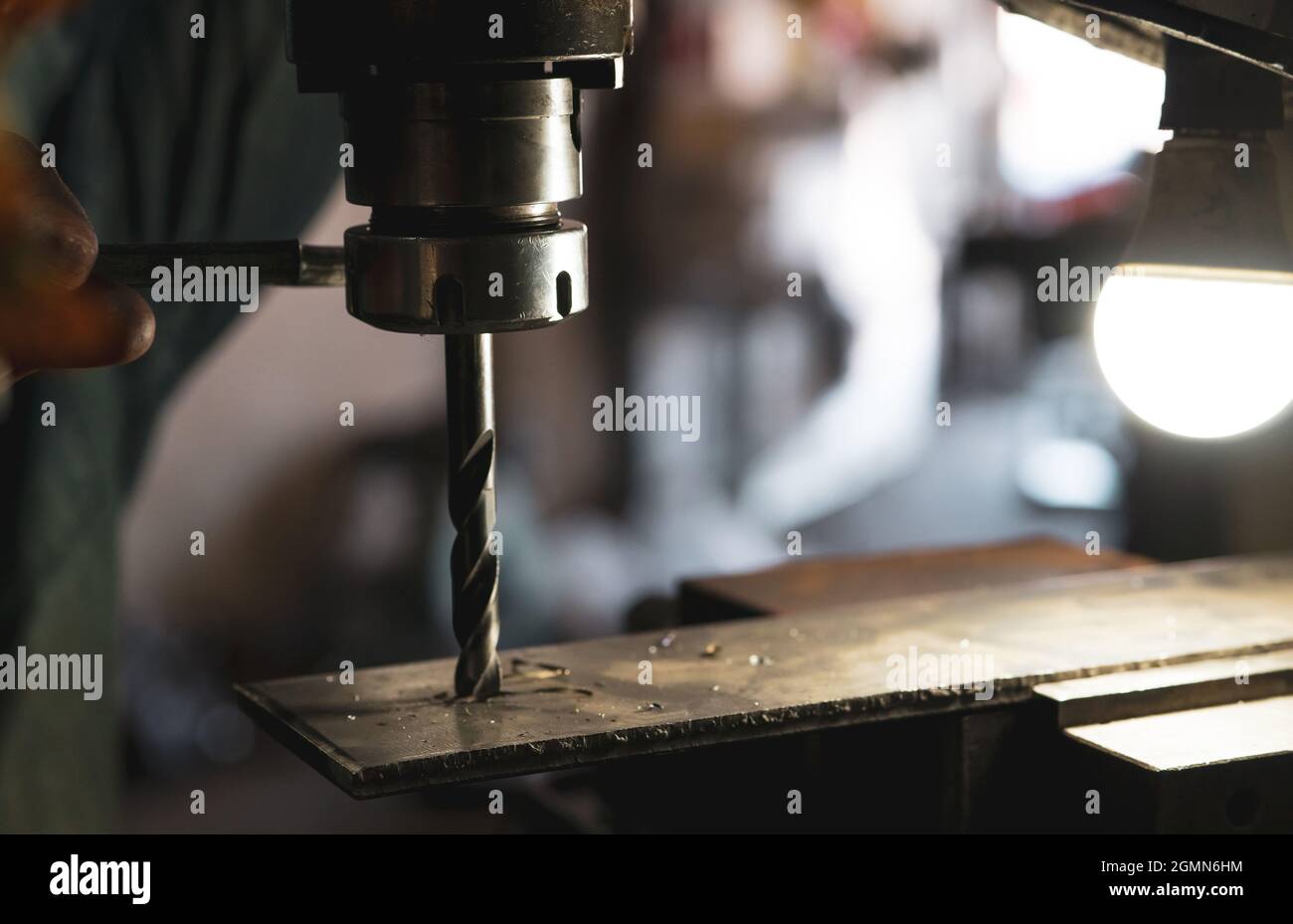 Worker hand working on milling machine to change metal drill bit. Tool
