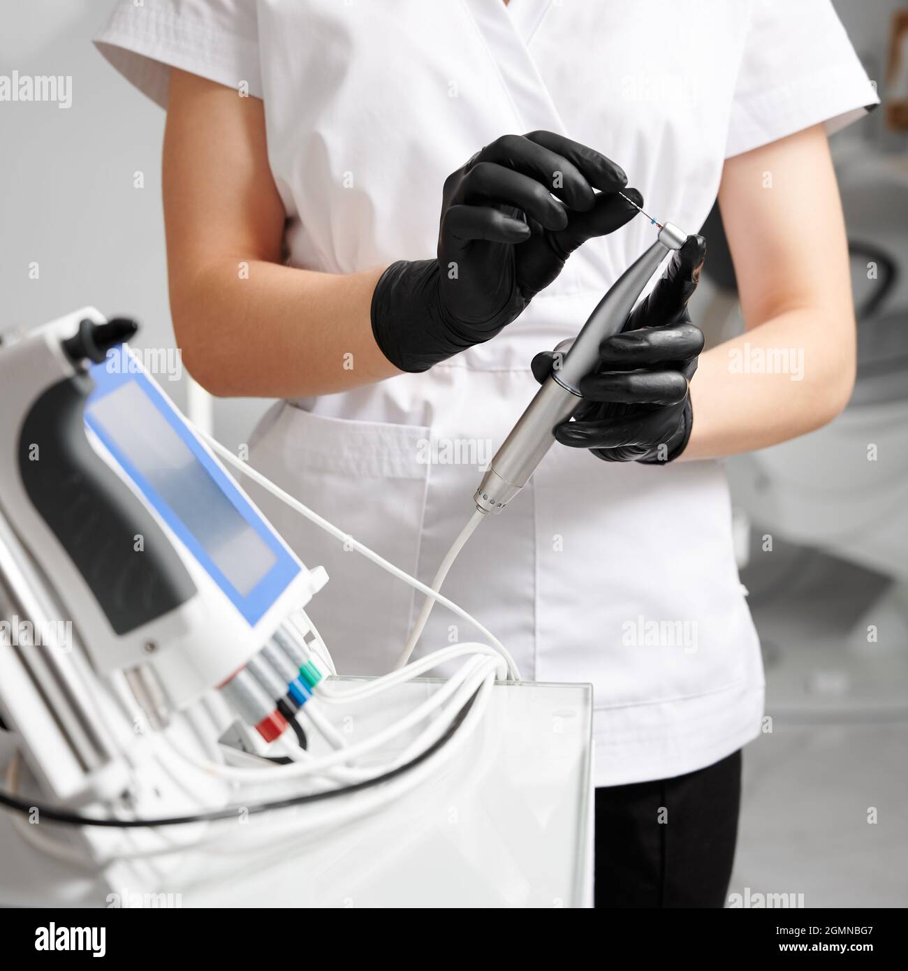 Close up of female doctor hands in sterile gloves holding endodontic endomotor for root canal treatment. Woman stomatologist preparing endodontic device for dental procedure. Concept of dentistry. Stock Photo