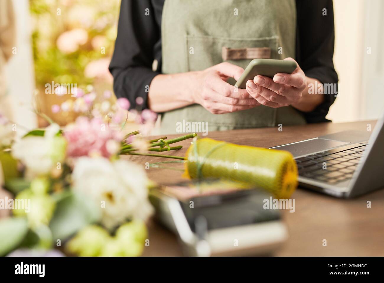 Cropped portrait of female small business owner using smartphone while managing flower shop, copy space Stock Photo