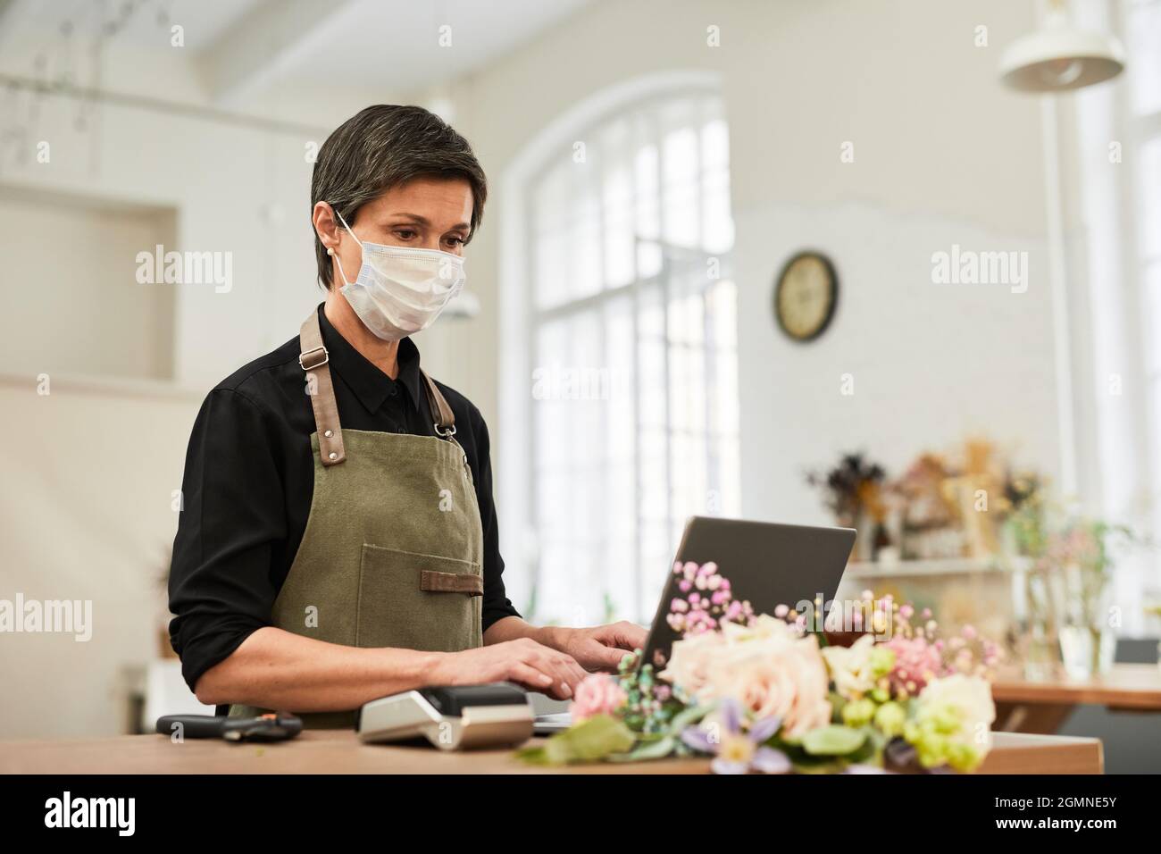 Portrait of mature woman using laptop in flower shop while managing small business, copy space Stock Photo