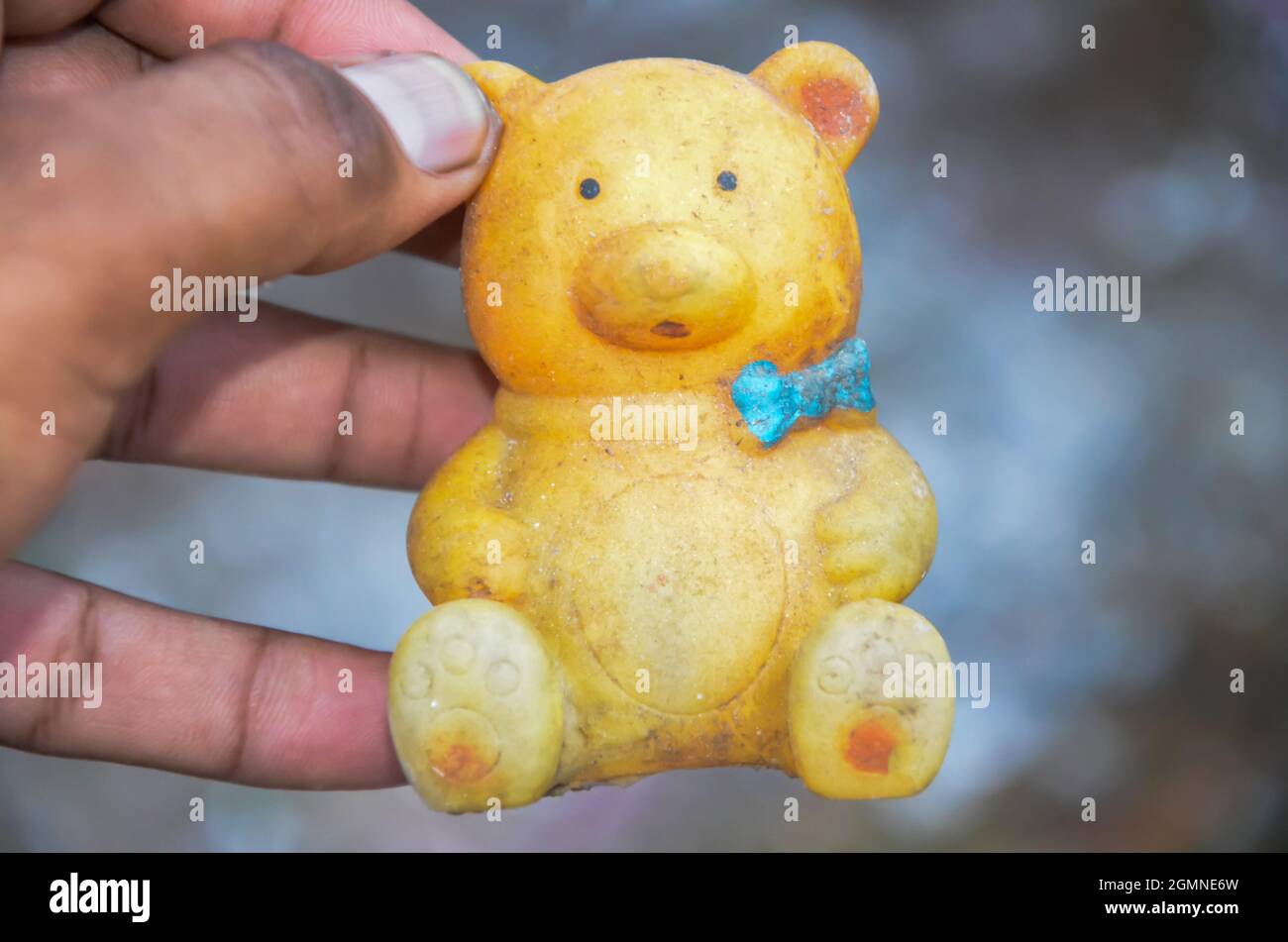Selective focus on yellow teddy bear in human hand isolated with blur background in the park in the morning sunlight in INDIA. Plastic teddy bear. Stock Photo
