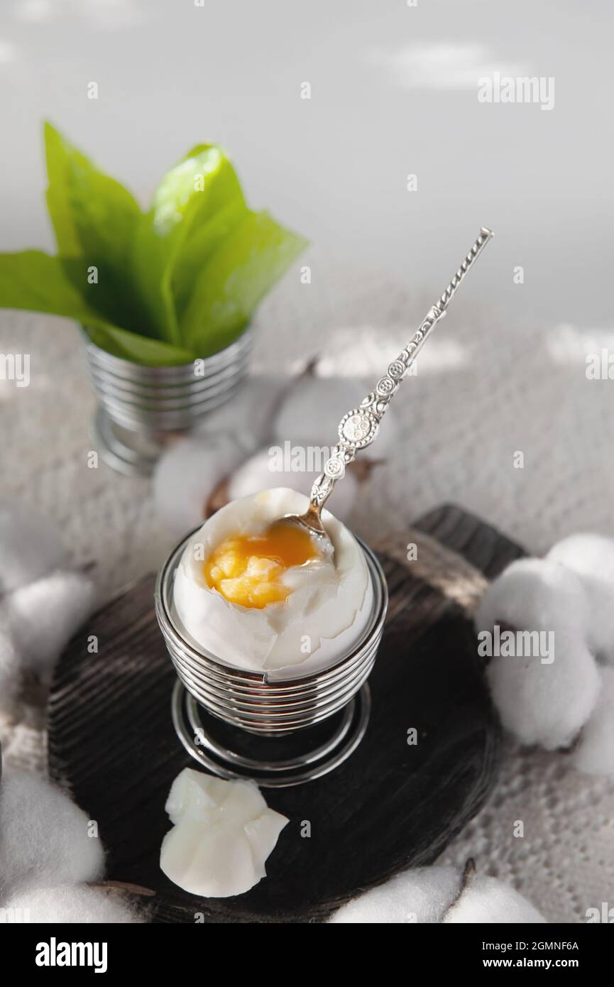 Open a soft-boiled egg in an egg cup. Homemade low-calorie breakfast on a rustic table. copy space. Stock Photo