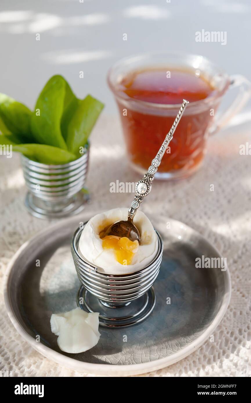 Open a soft-boiled egg in an egg cup. Homemade low-calorie breakfast with tea on a rustic table. copy space. Stock Photo