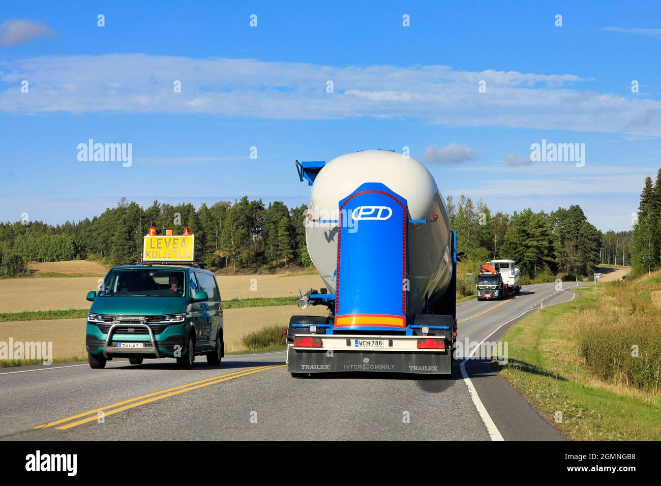 Pilot vehicle leads oversize load transport of a recreational boat, tank truck drives in opposite direction. Salo, Finland. September 9, 2021. Stock Photo